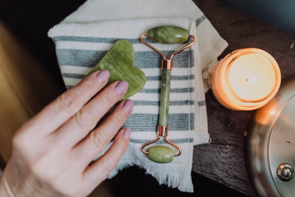 A serene spa setup with a jade roller, heart-shaped stone, and candle for relaxing self-care.