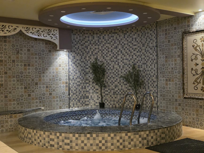 A serene indoor spa setting featuring a mosaic tiled jacuzzi with ambient lighting.